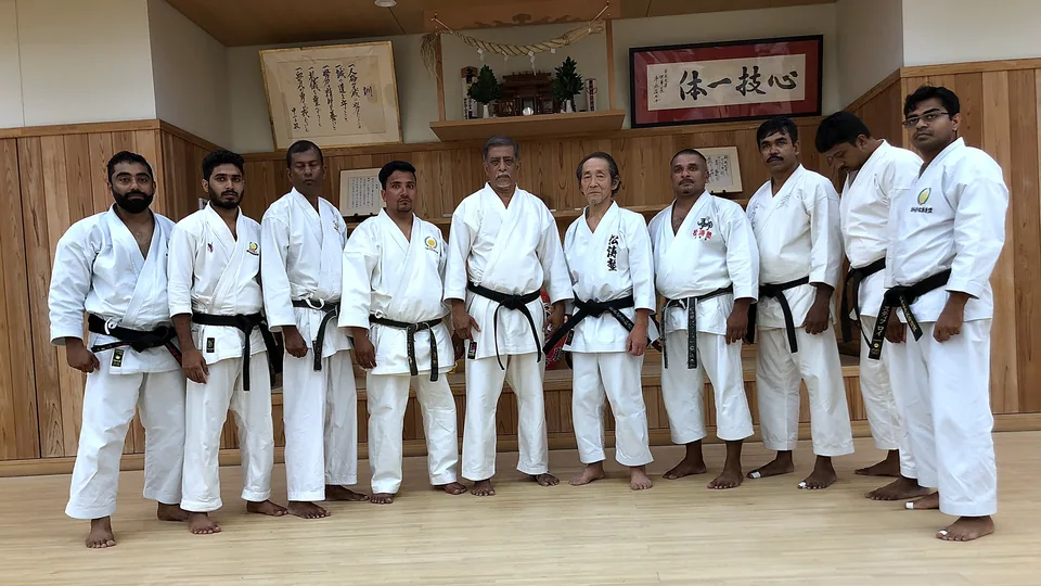 Line of black belts at a karate dojo in Japan, under the dojo calligraphy