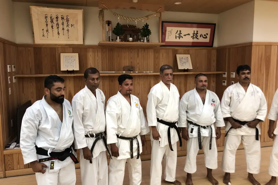 Black belts lined up before the kamiza of a dojo in Japan