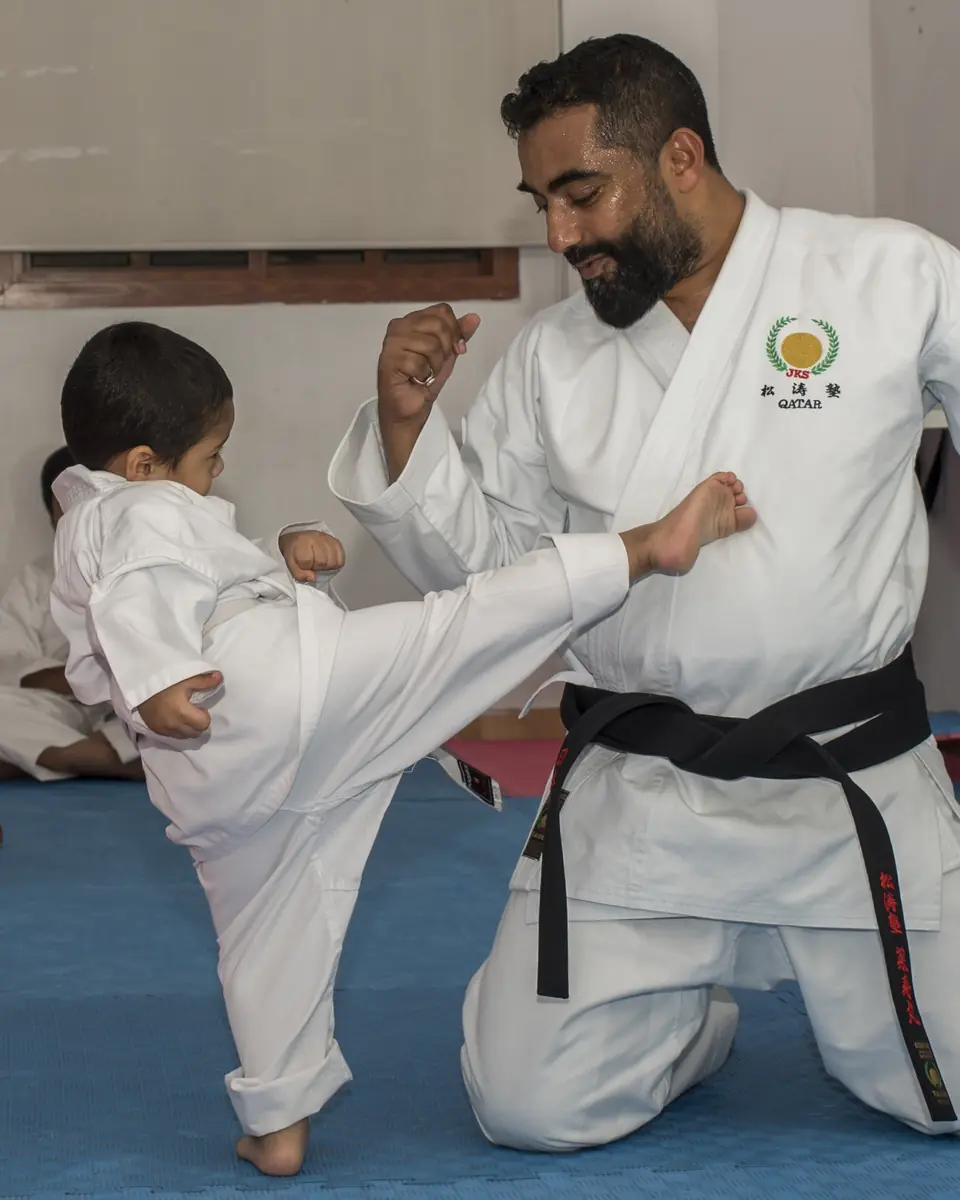 Sensei Najmal Ibrahim holding a front-kick drill with a young student