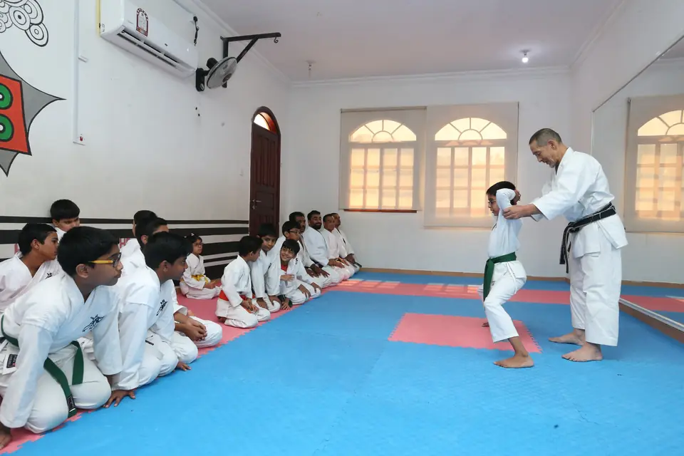 Sensei demonstrating a technique while students watch from seiza